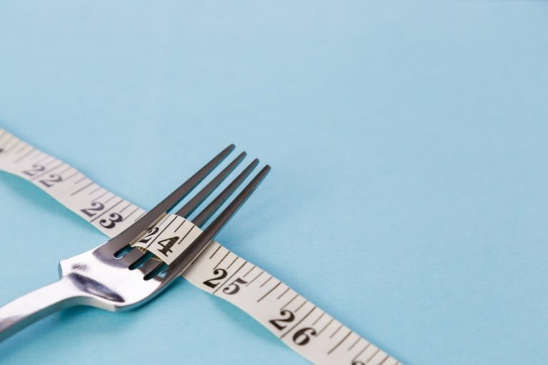 metal-dining-fork-and-inch-tape-on-color-background-symbolizes-weight-loss-free-space-for-text-no_t20_1QOARY-768x512