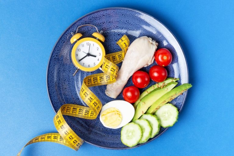 plate-with-vegetables-and-yellow-alarm-clock-on-blue-background-weight-loss-intermittent-fasting_t20_R0B4ov-768x512