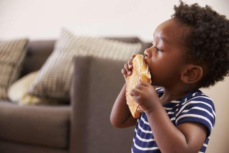 young-boy-eating-toasted-sandwich-at-home-PEVH3GD-768x512
